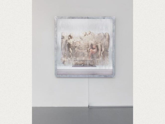 An art installation featuring a framed piece that appears to merge classical imagery with a contemporary presentation. The artwork is encased in a translucent material, with hints of Renaissance-style figures and soft, muted tones. A single red accent stands out amidst the grayscale composition, drawing attention to a central detail. The frame is mounted on a stark white wall with a visible cord running to the floor, creating a minimalist and modern gallery setting that contrasts with the classical theme of the artwork.